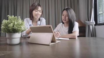 drahtloses Internet-Gerätekonzept, Fernlernen, während Sie aufgrund einer Coronavirus-Epidemie zu Hause bleiben, mit einem verschwommenen Hintergrund von zwei asiatischen Mädchen, die über Online-Unterricht diskutieren, weltweite Informationen