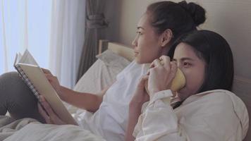Morning scene Asian two females lesbian couple spending happy time together, read review notes, lgbt homosexual equality life, lover relationship goal, apartment bedroom, breakfast morning tea video