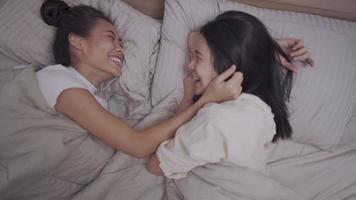 Asian two females lesbian couple cuddle inside blanket, holding hands hug kissing, girlfriend smile laugh, LGBTQ pride happy relationship, homosexual society concept, camera above shot high angle view video