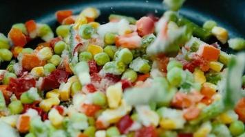 les légumes surgelés pour la friture tombent dans la poêle. super ralenti. cuisiner des aliments sains dans la cuisine à domicile video