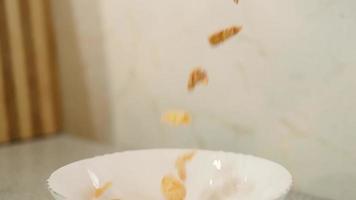 los copos de maíz caen en un tazón. cámara súper lenta. cereal de desayuno saludable sin gluten. video
