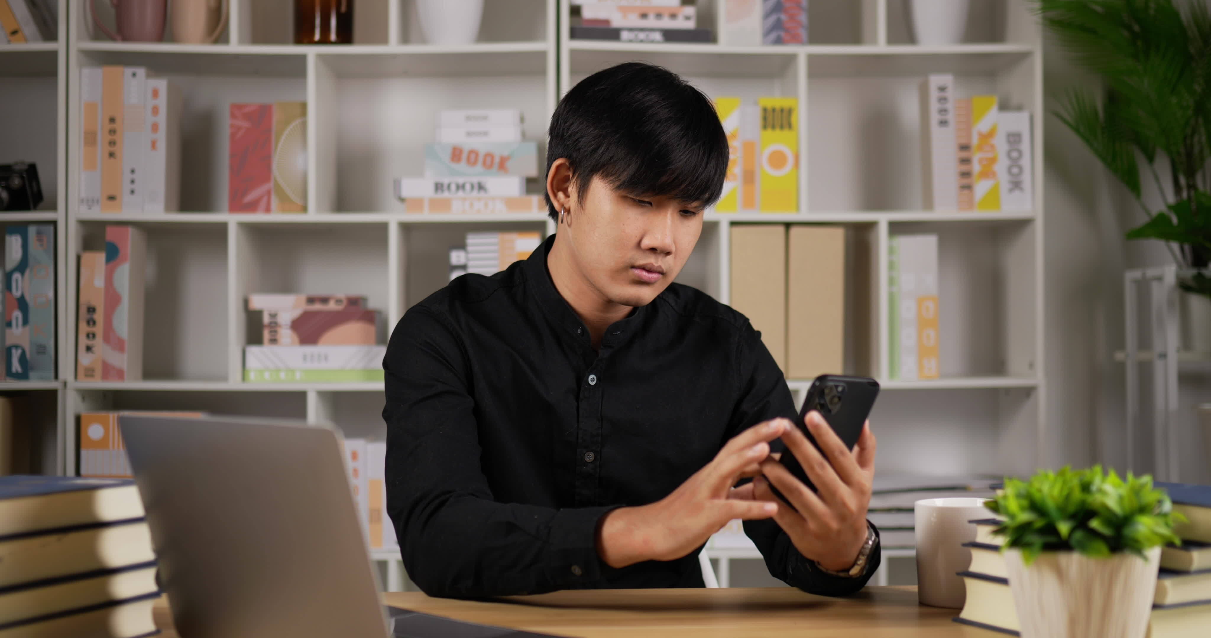 Phone, thinking and man by office window for career inspiration, job search  or online networking. Contemplating asian person or young entrepreneur  cellphone, smartphone or mobile app in workplace Stock Photo