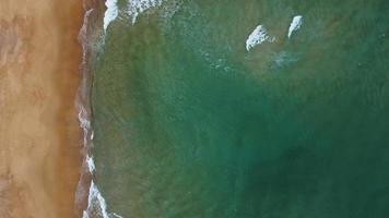 Flygfoto över den vita sandstranden och vattenytans struktur. skummande vågor med himmel. vacker tropisk strand. fantastisk sandstrand med vita havsvågor. natur, havsbild och sommar koncept. zooma in. video