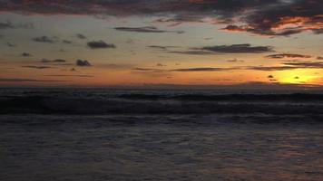 hermosa puesta de sol playa de arena del océano y textura de la superficie del agua. olas espumosas con cielo y nubes. hermosa playa tropical. increíble costa de arena con olas de mar blanco. concepto de naturaleza y verano. video