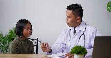 portrait d'un médecin de sexe masculin asiatique consultant une patiente à la clinique. les enfants à voir le médecin professionnel. médecin décrivant l'état du patient. concept de soins de santé, d'assurance et de médecine. video