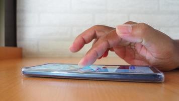 vista laterale della mano dell'uomo che utilizza lo smartphone nella caffetteria per cercare informazioni video