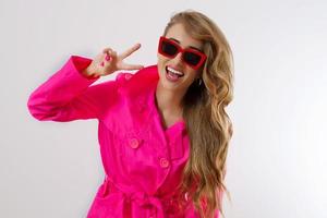 Happy, shock, excited woman face closeup. Peace sign. Girl bright pink autumn clothes, red sunglasses isolated. white background, copy space. Beautiful female surprised cheerful. funny model screaming photo