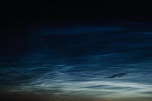 Noctilucent mesospheric clouds in night sky. Rare atmospheric phenomenon over city. photo