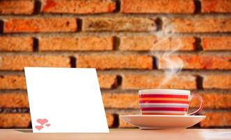 A bright pink metallic coffee cup on vacation.  And there is a blank sheet of note paper for inserting the contents. mock up and copy space photo