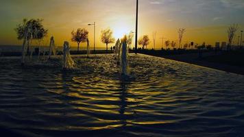 fontana d'acqua e silhouette di persone al tramonto video