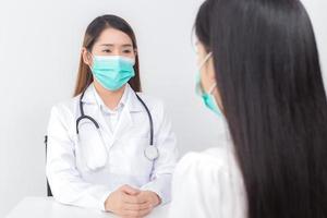 Asian woman doctor is talking with her patient to consult and check symptom which wears medical face mask always diagnostic in new normal and health care concept. photo