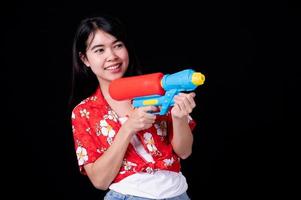 Hermosas mujeres asiáticas sostienen pistolas de agua de plástico en un antiguo templo durante Songkran, el festival de agua más hermoso y divertido de Tailandia foto