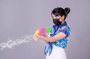 A beautiful Asian woman shows a gesture while holding a plastic water gun during the Songkran festival photo