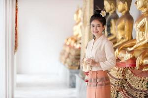 Thai beautiful women in traditional Thai dress use fresh flower garlands to pay homage to the Buddha image, To make a wish on the Thai Songkran Festival photo