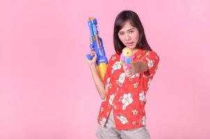 A beautiful Asian woman shows a gesture while holding a plastic water gun during the Songkran festival photo