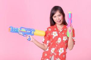 A beautiful Asian woman shows a gesture while holding a plastic water gun during the Songkran festival photo