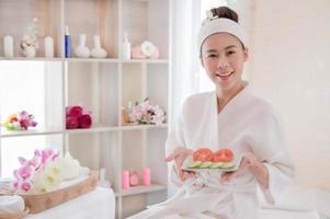 A beautiful Asian woman prepares to use tomatoes and cucumbers for facial care