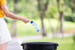 la mujer arrojó una botella de agua de plástico después de beber toda el agua a la basura preparada para su almacenamiento y reciclaje