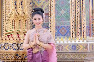 A beautiful, graceful Thai woman in Thai dress adorned with valuable jewelry raise her hand to pay respect photo
