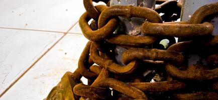 Yellow corroded iron chain wrapped around on the iron pole. photo