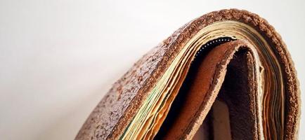 An old brown orange synthetic wallet with some money inside on the dim grey yellow background. photo