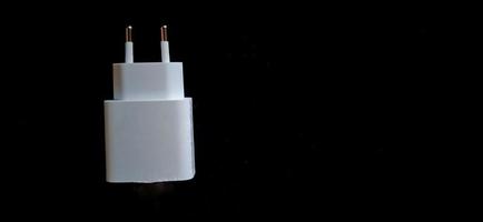 White smartphone charger on the black background. Smartphone charging electronic device. photo