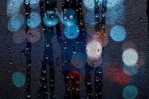 gotas de lluvia en la ventana y luces de la calle en la noche