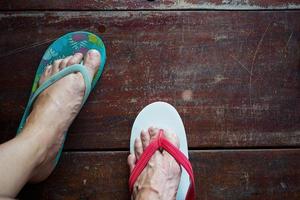 Top view pair of foot in the sandals stand on the wooden floor photo