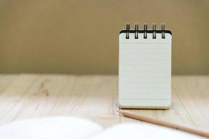 Small note book paper or notepad stand for writing information with pencil and book on wood table photo