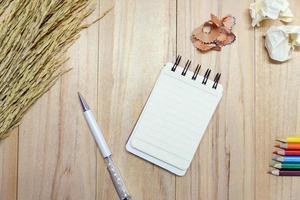 Small note book paper or notepad for writing information with pen, color pencil and crumpled paper balls on wooden table. view from above photo