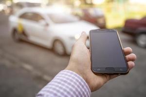 the hand with the phone in hand on the background of taxi car photo