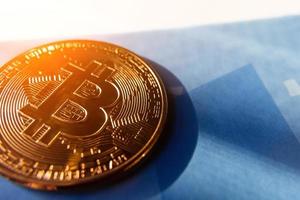 bitcoin coin on a blue background with a glare of the sun. photo