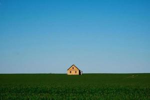 house on a green field and blue sky photo