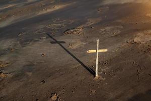 wooden Christian cross on the beach, behind the inscription SOS photo