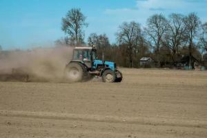 Farmer in tractor preparing land with seedbed cultivator photo