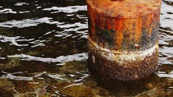 poste de muelle oxidado en agua de mar