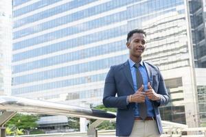 Business people thumbs up for acceptance. Portrait of an handsome businessman. Modern businessman. Confident young man in full suit standing outdoors looking away with cityscape