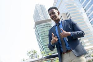 Business people thumbs up for acceptance. Portrait of an handsome businessman. Modern businessman. Confident young man in full suit standing outdoors looking away with cityscape
