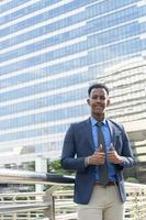 Business people thumbs up for acceptance. Portrait of an handsome businessman. Modern businessman. Confident young man in full suit standing outdoors looking away with cityscape photo