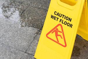 señal amarilla de precaución resbaladiza en el suelo mojado