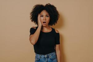 Studio portrait of young shocked african female with unexpected facial expression photo