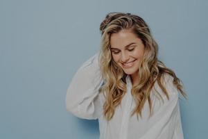 Romantic young blonde woman looking down with tender smile photo