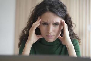 Preocupada joven empleada italiana mirando la pantalla de la computadora con expresión de cara frustrada foto