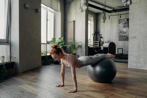 feliz mujer sana balanceándose en la pelota de ejercicio durante el entrenamiento de fitness
