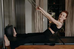 Young beautifull woman with smile doing exercises on pilates reformer