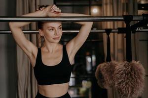 Young beautifull woman in leisure pose leaning forward on frame of pilates machine photo