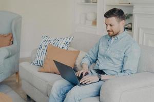 Young businessman working from home while sitting on couch photo