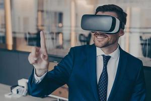 Smiling young finacier in formal suit enjoying spending time in virtual reality with VR headset photo