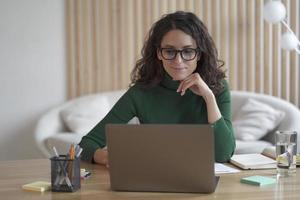 Young pleasant Italian woman freelancer working on laptop computer remotely at home