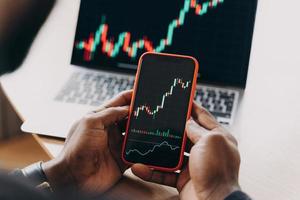 African man stock trader holding smartphone with financial charts and trading online investment data photo